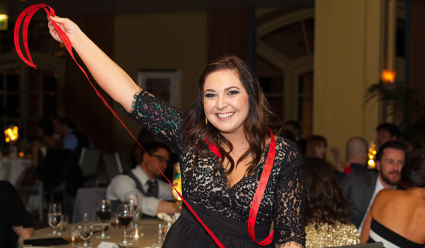 Woman in dress holding long row of connected paper tickets in outstretched arms