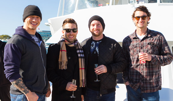 4 men standing in front of yacht on pier